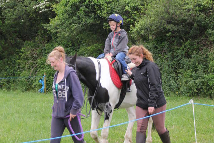 Photograph of two girls leading child on pony ride at Kinsale races